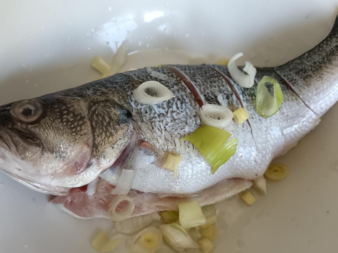 今日分享清蒸鲈鱼：鲈鱼收拾干净，花刀，放葱姜沫、少许食盐腌制十五分钟，放鱼盘待