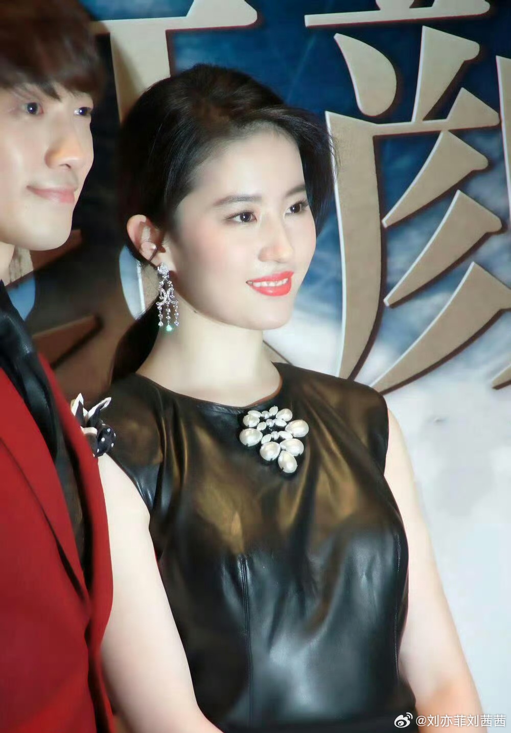 刘亦菲身着一袭黑色无袖皮质连衣裙，利落剪裁勾勒出流畅肩颈线条，哑光与亮面交织的皮