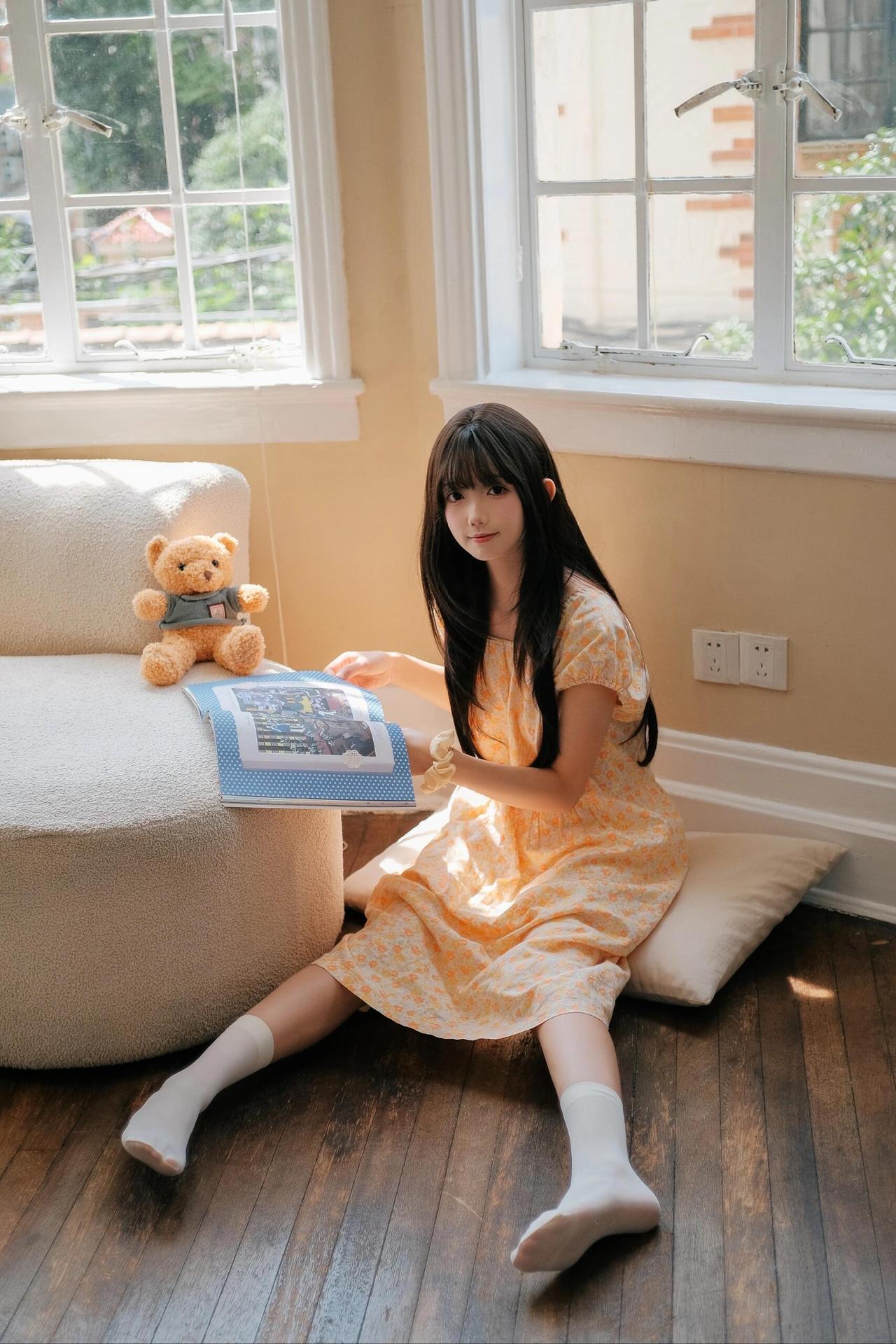 小女孩坐在地上看书，阳光明媚。