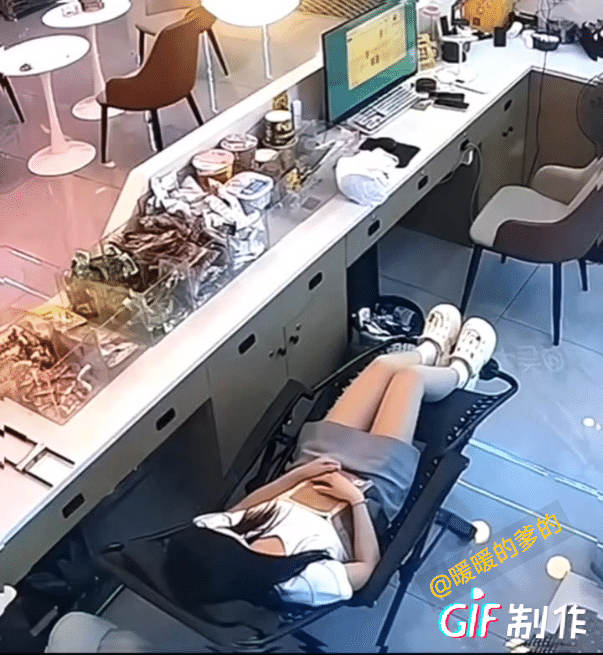 中午，由于店里也没啥客人，一女子在吧台里面躺椅上休息，大概率是睡着了。监控拍摄到