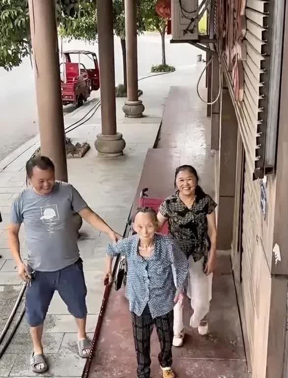 男子把轮椅上86岁的母亲推到监控下边，让她站起来拄着拐杖往前走了几步，而自己则在