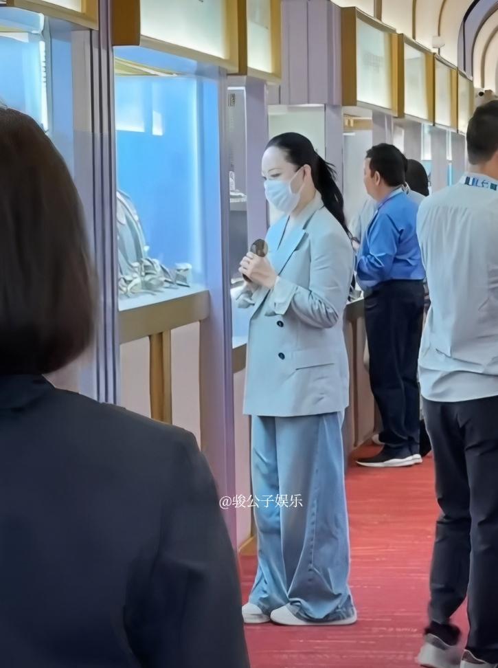 章小蕙近日现身香港珠宝展，只见她穿着浅色外套配蓝色裤子，一头黑发随意扎起来，精气