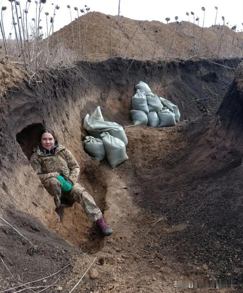 俄乌战场上的一名乌克兰女兵，正在躲在简易战壕里休息，或许她也知道这场战争有多么残