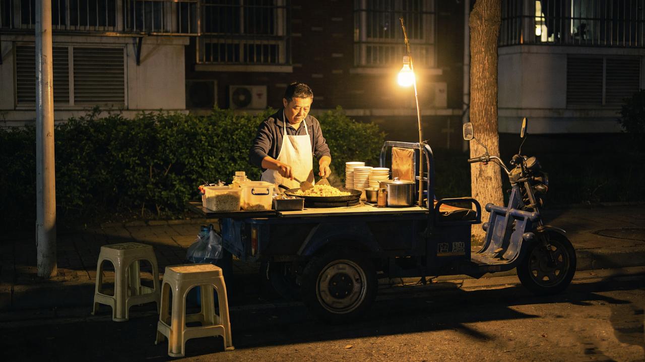 老周在小区门口卖炒饭八年。昨晚收摊前，一个穿西装的男人走过来，要了份最便宜的蛋