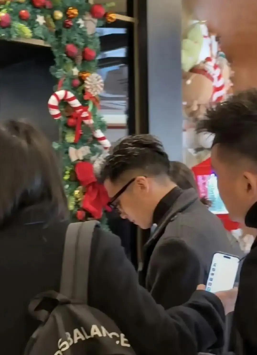 44岁谢霆锋在哈尔滨中央大街被拍。他单手插兜嚼着糖葫芦，身后助理拖着两大箱红肠。