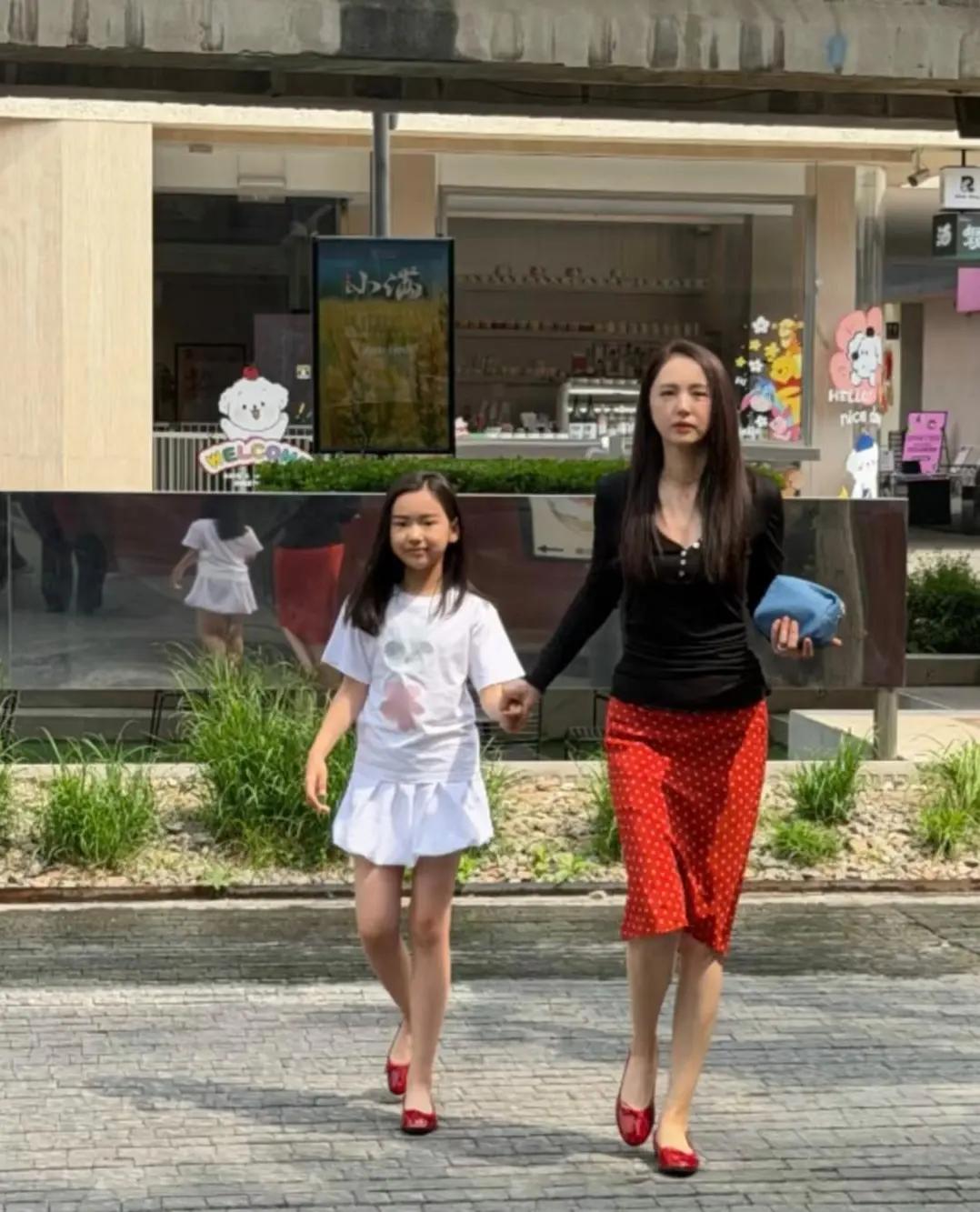 董璇带着女儿外出购物，董璇手拉着女儿，昂首挺胸走在街上，两人边走边聊天，看起来非