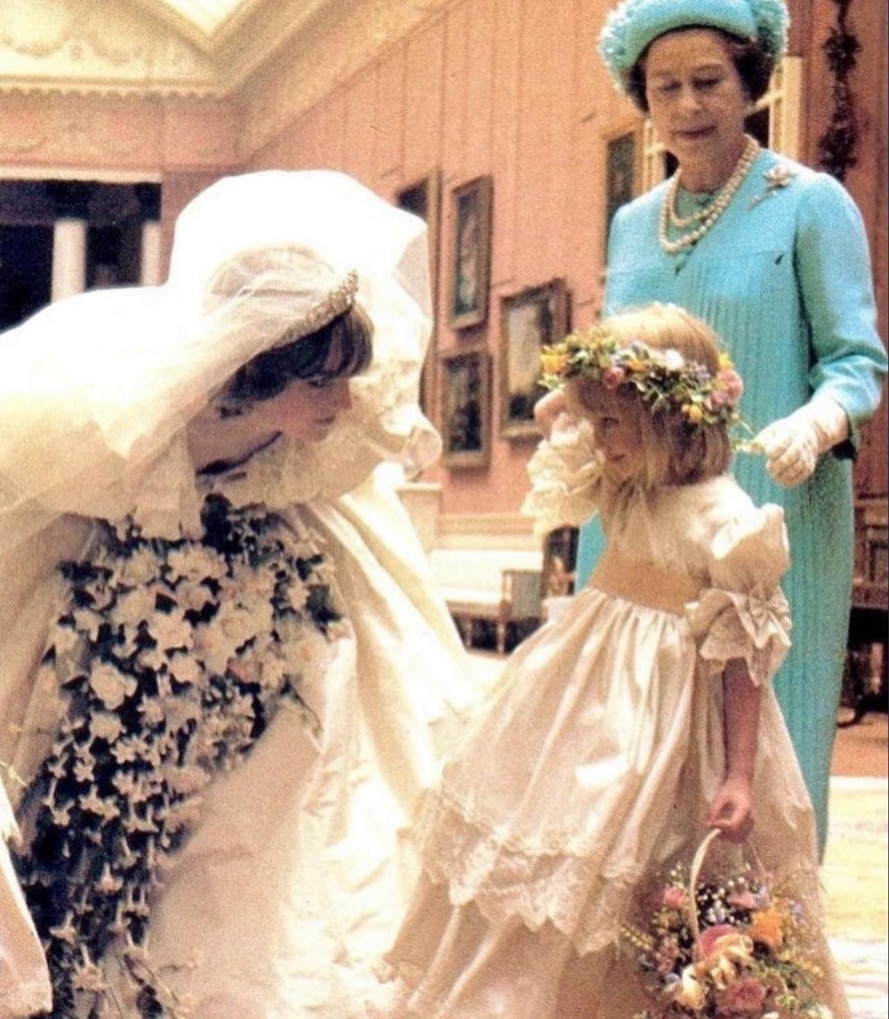 1981年7月29日，圣保罗教堂，穿着婚纱的戴安娜王妃俯下身子和花童互动，女王在