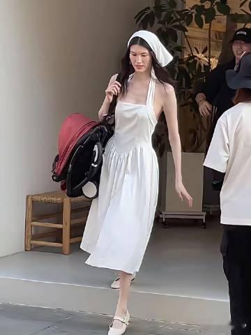 何穗身穿一身白推着婴儿车，也许是想营造出油画田园少女风吧，头上还搭配着...