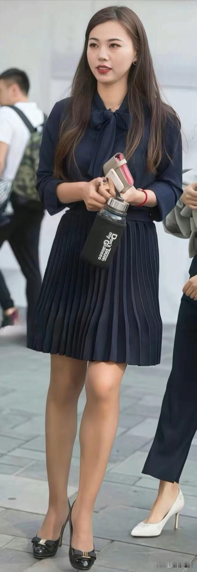 街头偶遇一位穿藏青色百褶裙的姑娘，气质清爽又利落，简单的穿搭也能让人眼前一亮。