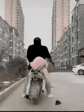 女孩上学时，一只鞋子掉在了地上，她赶紧下车去捡鞋子。这时，爸爸坐在电动车上，