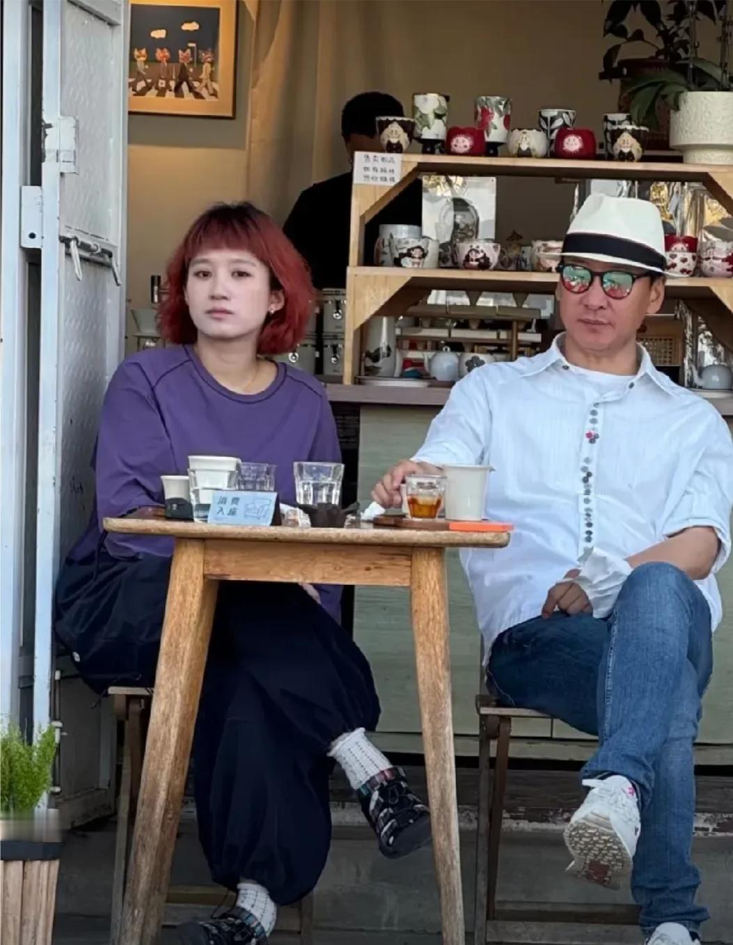 55岁的周杰在云南大理被网友偶遇，他和一位美女在茶馆喝茶，他穿着白衬衫，头戴着帽
