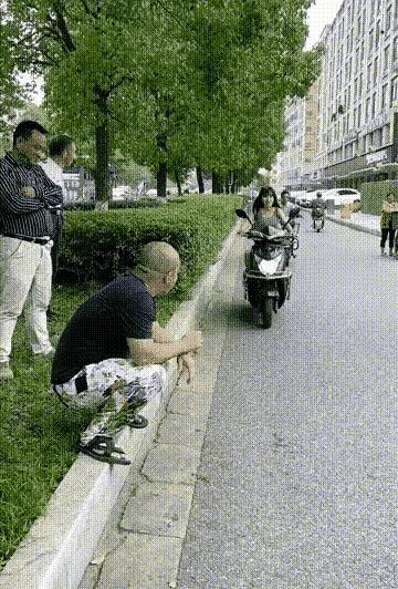 一位大爷蹲在路边等着碰瓷，看到一个美女骑着电动车过来，急忙起身躺在女孩车前，一手