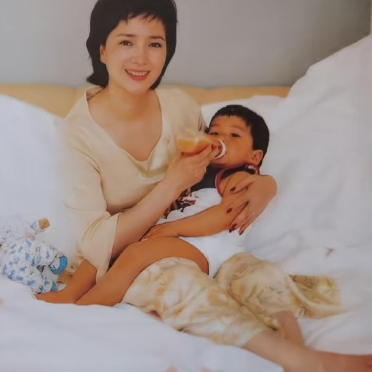 2001年，何晴在卧室带孩子，一张温馨的合影，从镜头中我们可以看到，何晴手里拿着
