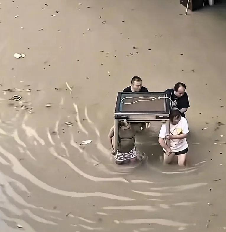 麻将桌∽洪水袭来警声急，帅哥无奈把财弃。冰箱衣机不用动，麻将桌子更贵重。众人顶