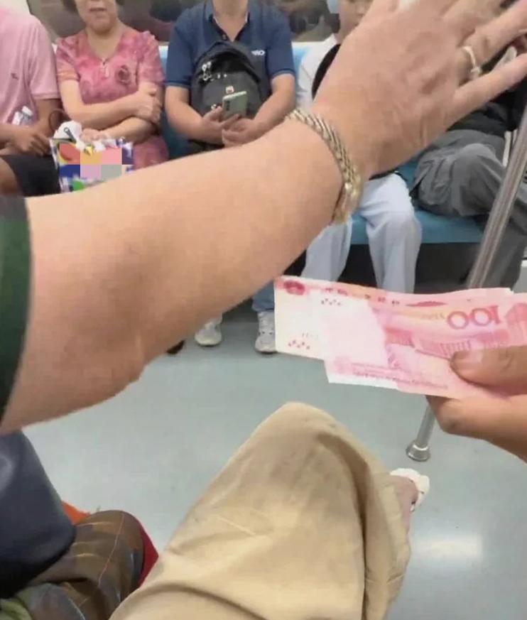 地铁上，一位男孩拿着500块现金，递给旁边的陌生奶奶，奶奶连忙摆手拒绝，并一把推