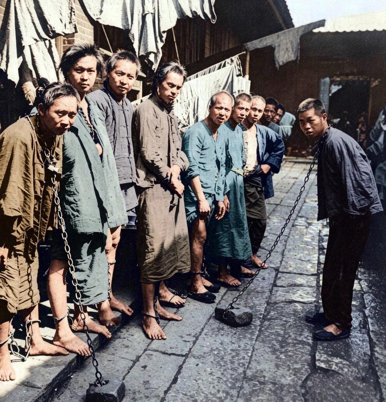 1901年，广州监狱，一群被关押的义和团员，赤着的双脚，身上挂着铁链颈锁和脚镣。