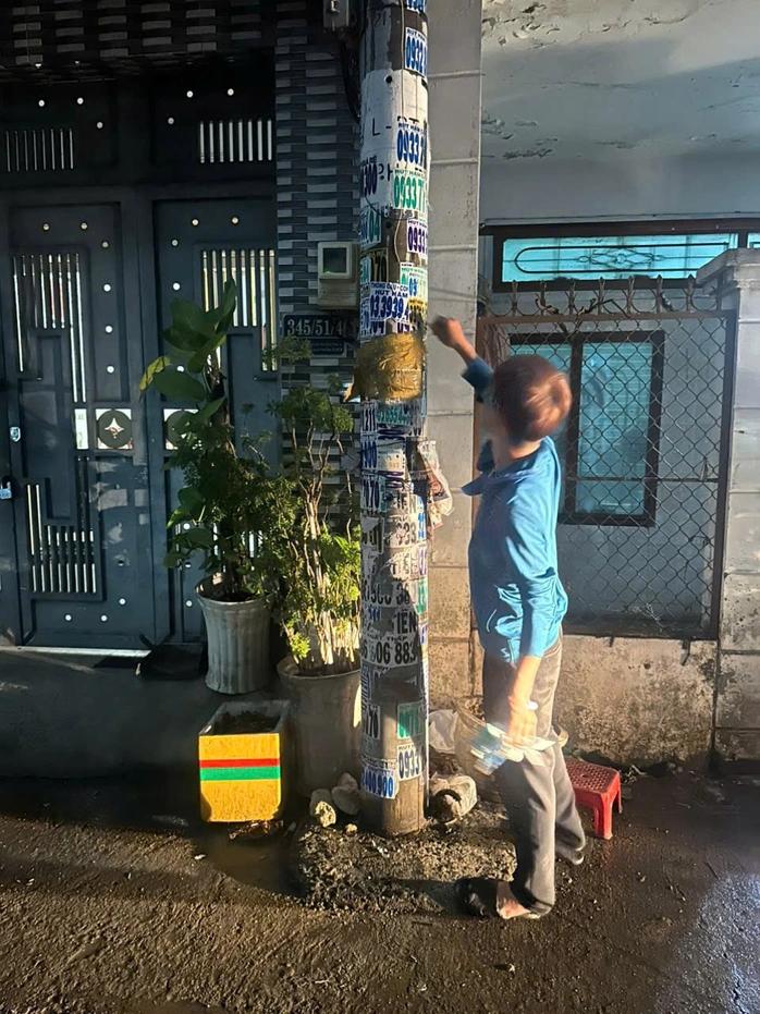 越南胡志明市一青年在电线杆上铁非法广告被警察当场抓获并受到行政处罚5月8