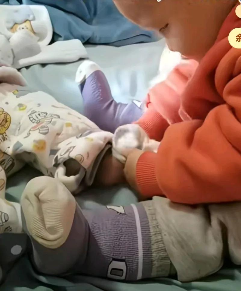 哥哥坐在床上给妹妹穿袜子，穿来穿去穿不进去，还发出质疑的声音，心想这袜子咋这