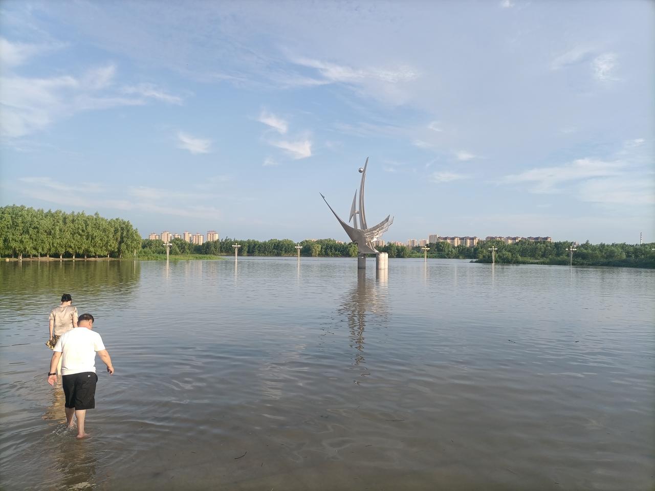 【公园涨水即景】辽澜漫入游园场，鹤塑亭亭碧水央。浅岸游人