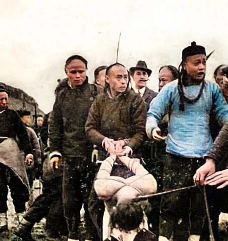 1900年，菜市口刑场，一个肌肉发达的年轻男子跪在地上，双臂被五花大绑着高高架起