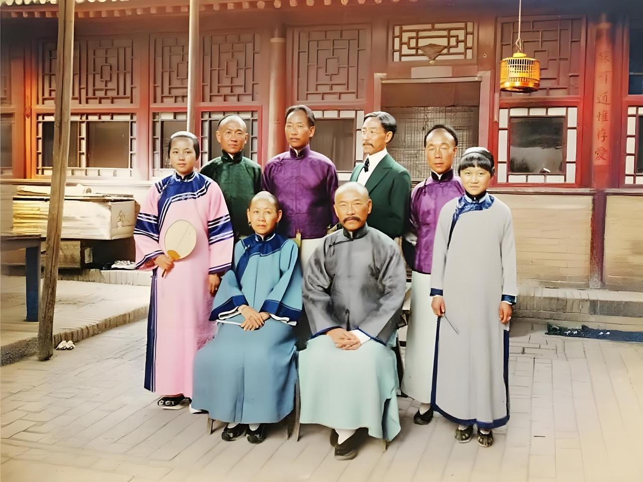 清末的一处四合院院落里，一个旗人家庭正在合影。院落铺着砖石地面，背景是带有传统木