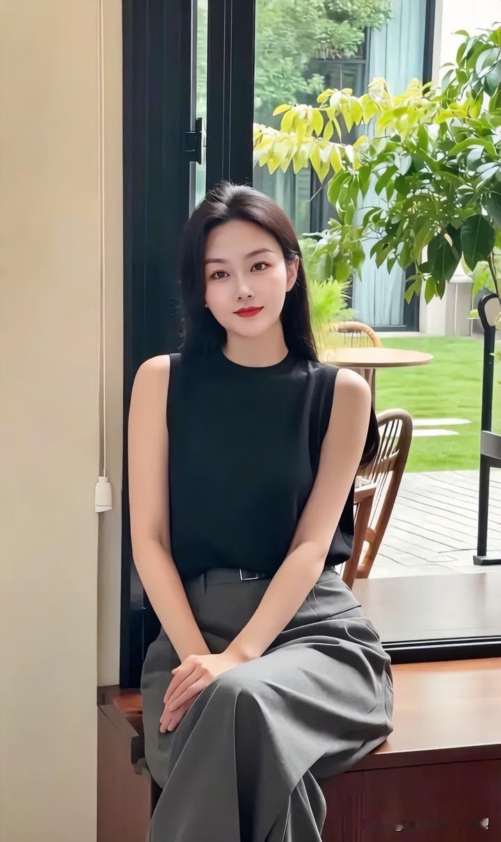 室内的沉稳与窗外的生机悄然对话。她身着素衣，长发披肩，嘴角噙着一抹淡淡的笑意。这