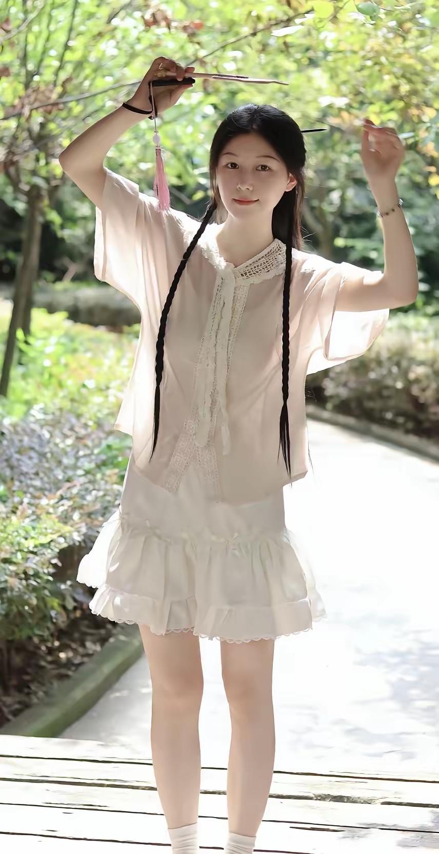 蕾丝衬得裙角都软乎乎的，双麻花辫垂在肩头，摇扇那下连树荫里的光都跟着甜了，是把春