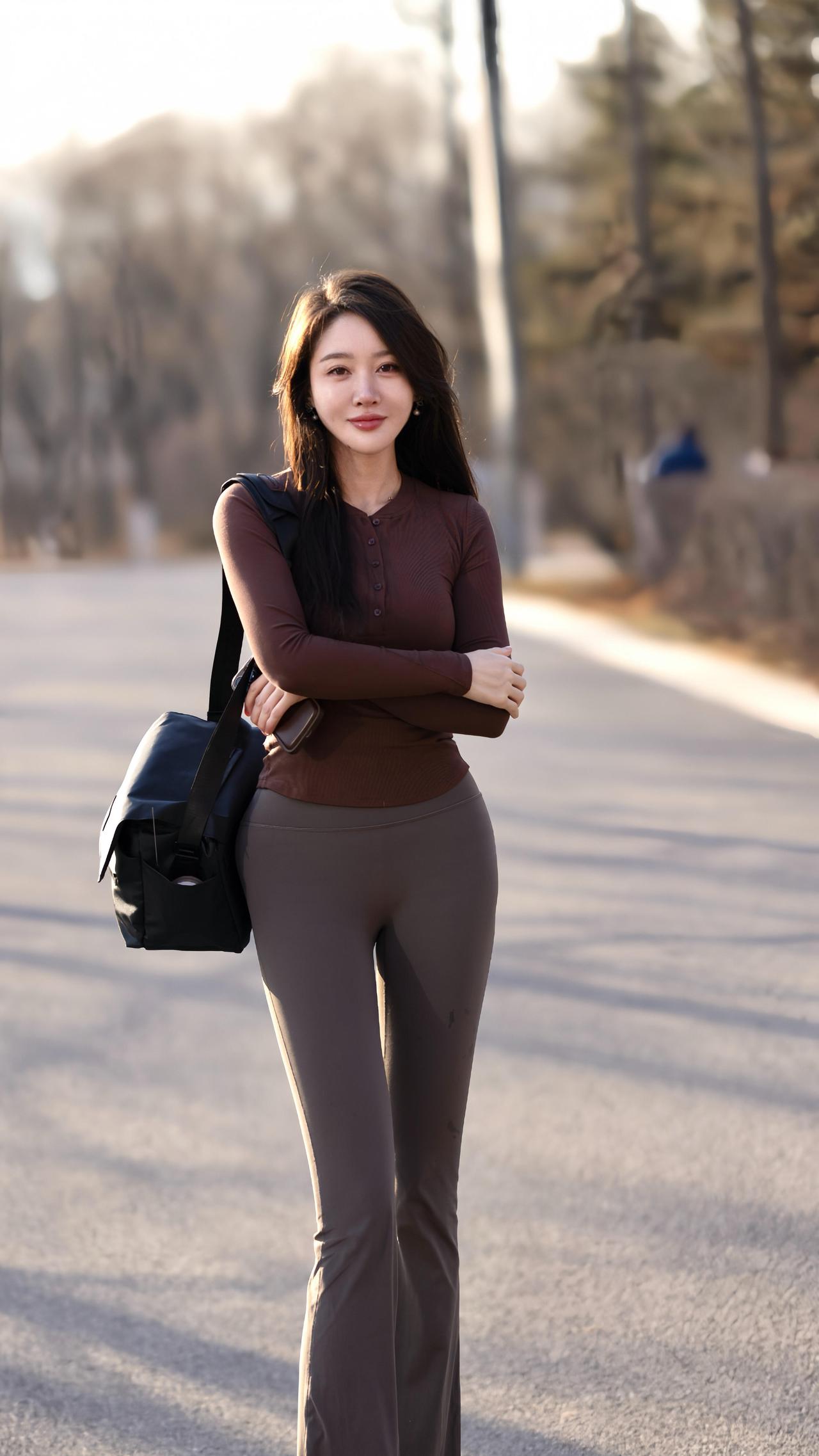 焦糖色的针织衫裹住初冬的风深灰裤脚漫过路面的光影她站在空阔的路上双臂轻拢，