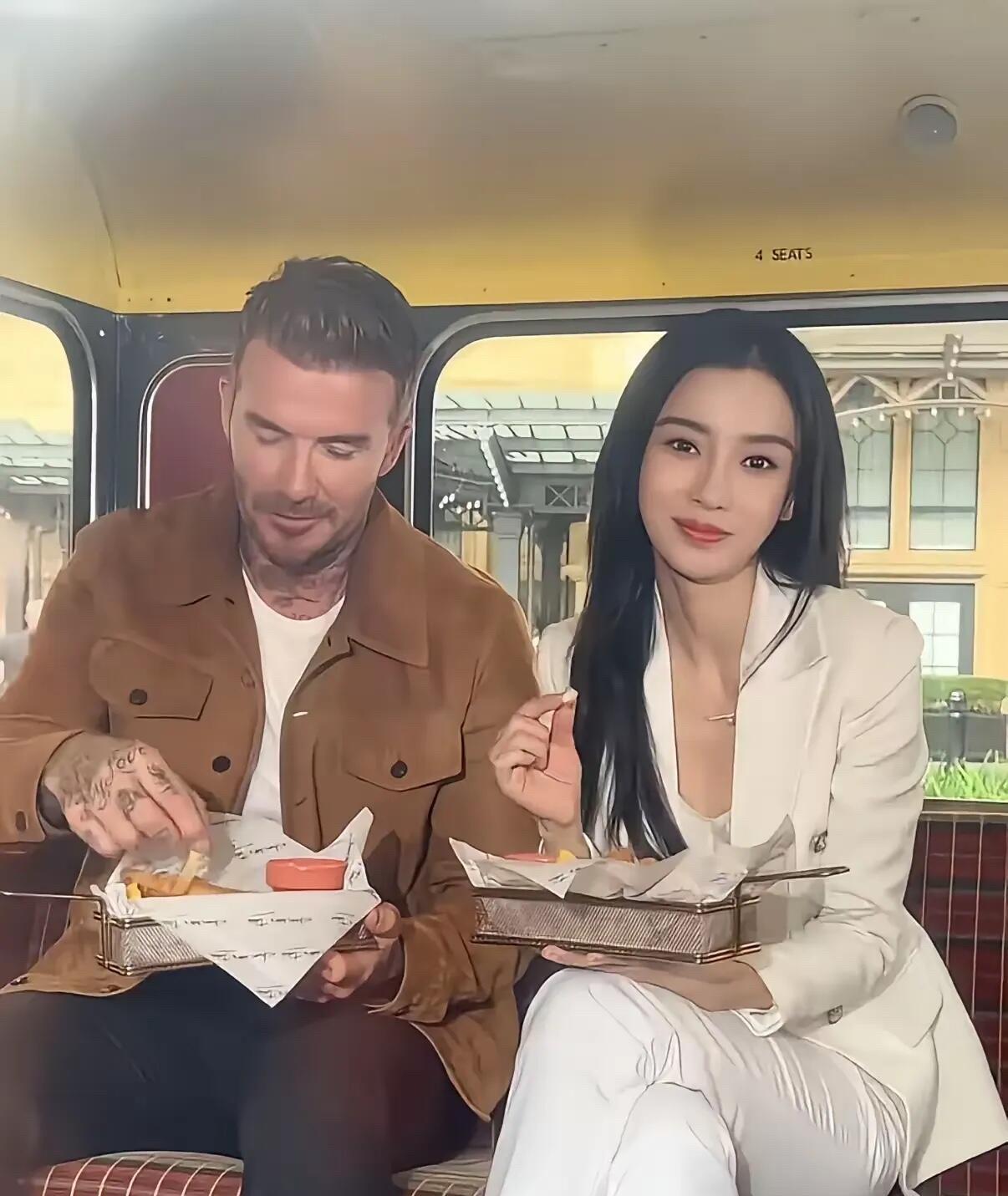 估计照片中的美女心里已经乐开花了，毕竟能跟巨星贝克汉姆坐在一起吃东西，应该是很多