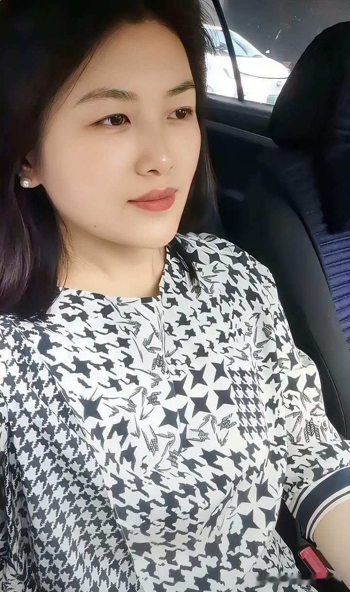 光影透过车窗洒落，勾勒出恬静的侧颜。耳畔的珍珠温润如玉，眼眸中藏着一片宁静的海。