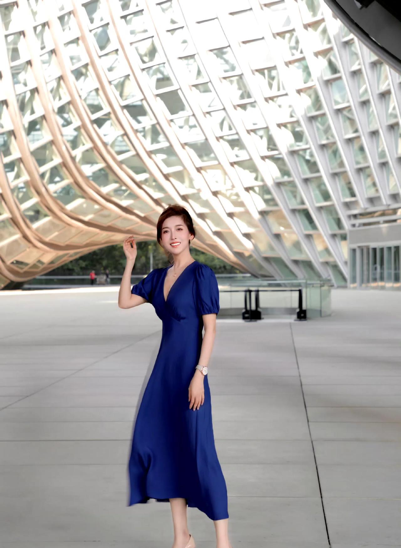 靛蓝裙裾拂过都市光影，建筑棱线与裙身柔弧对话，每一步都漾起从容优雅，钢筋森林间，