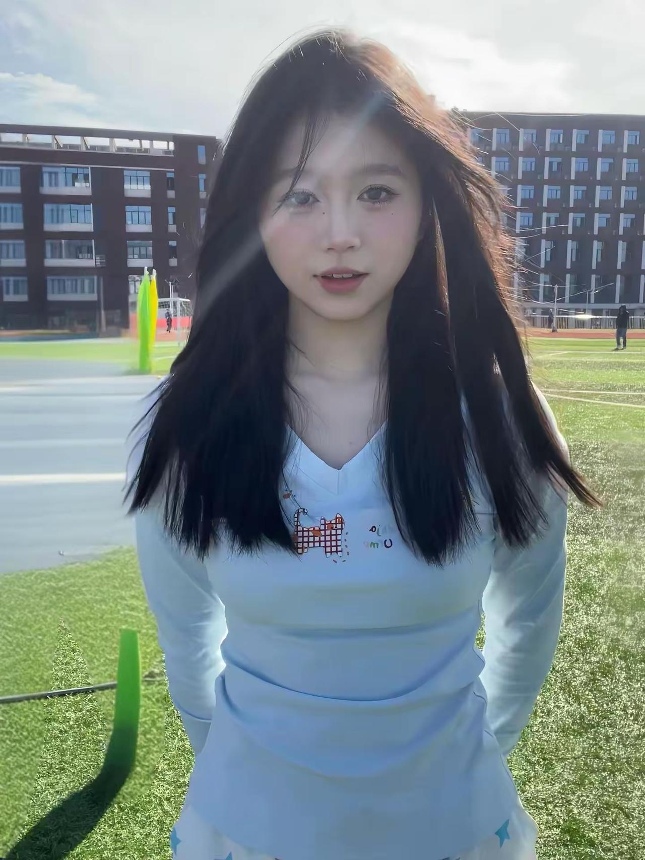 操场的风把发梢吹得软乎乎，衣摆上的小猫咪跟着阳光晃。身后的跑道还沾着体育课的热气