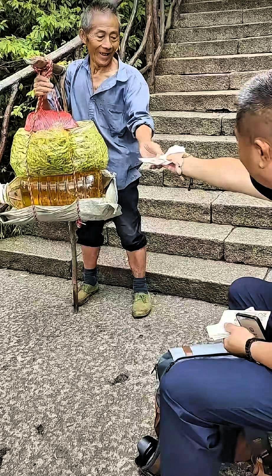 泰山十八盘的石阶上，一位歇脚的江苏游客，对着迎面走来的挑山工做了个动作，瞬间让周