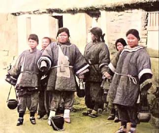 这张老照片拍摄于1898年3月，地点是在山东青岛。一群妇女站在茅房旁，她们个个穿