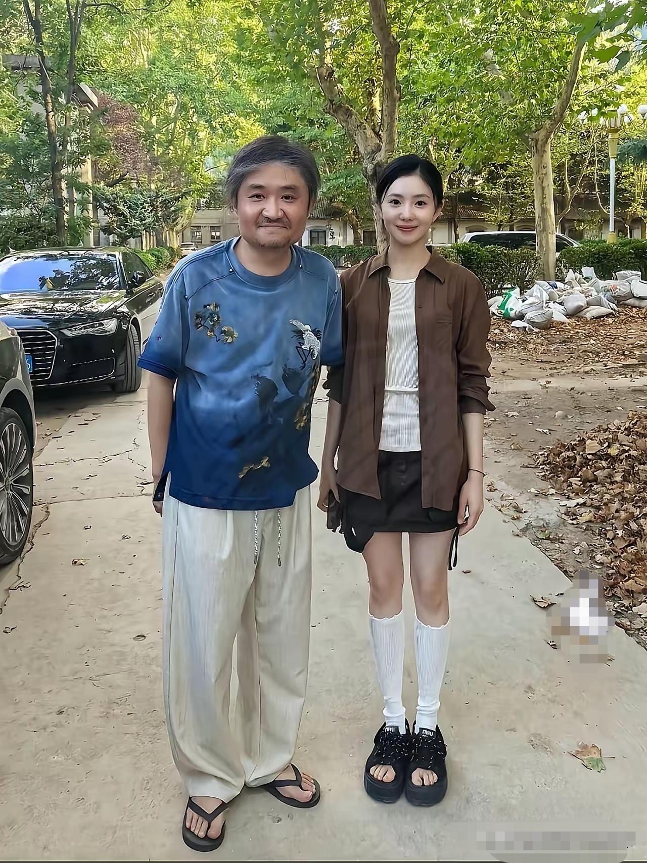 相声演员苗阜与刘浩存的合影，苗阜穿着人字拖，头发花白，身体微微前倾，刘浩存站立得