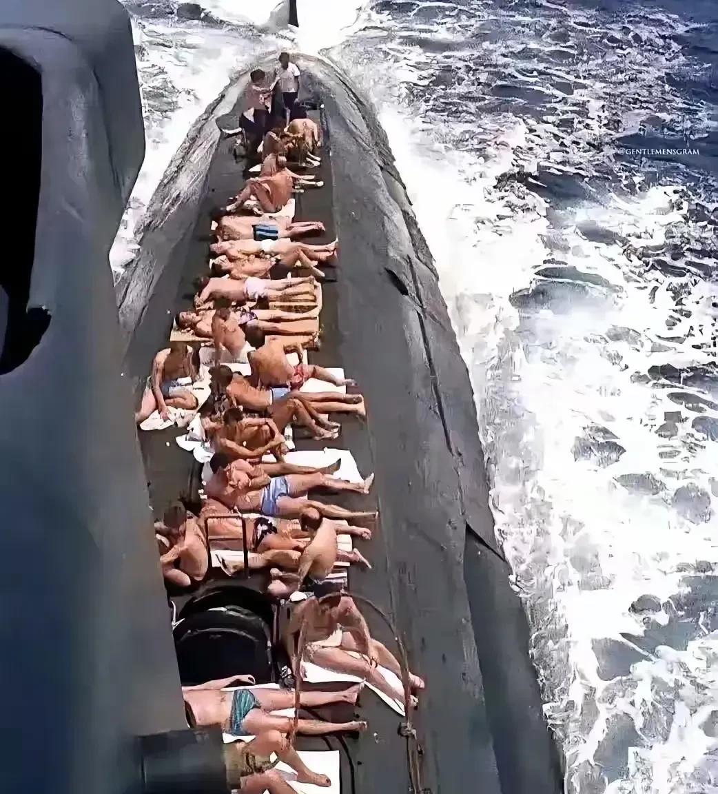 这是一艘潜艇浮出水面，趁着天气正好，水兵们钻出狭窄的舰艇，来到甲板上晒太阳，每个