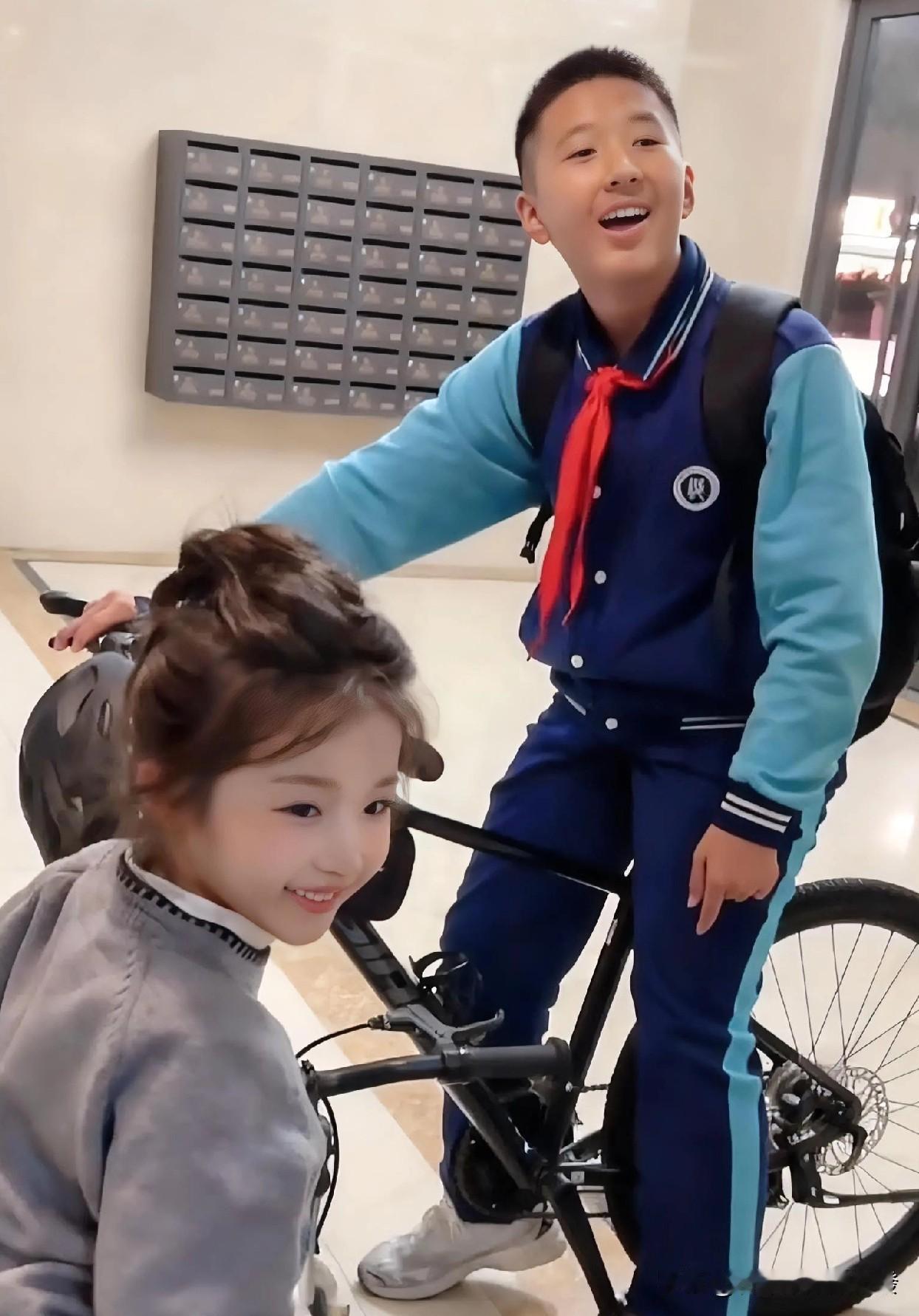 男孩和妹妹推着车刚从电梯出来，就碰见了自己的同学，随即指着漂亮的妹妹给同学炫耀：