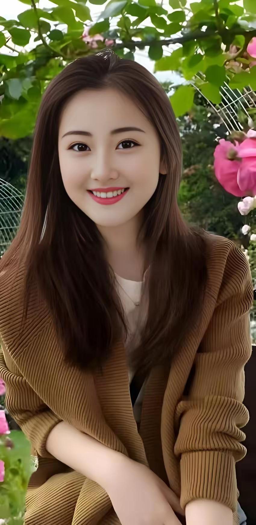 阳光明媚的午后，微笑的少女与盛开的花朵相映成趣。