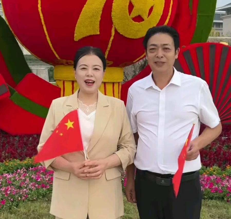 许敏老姚今天手里挥舞着小红旗，着装整洁，而庄重，后面就是国庆期16周年的LOGO