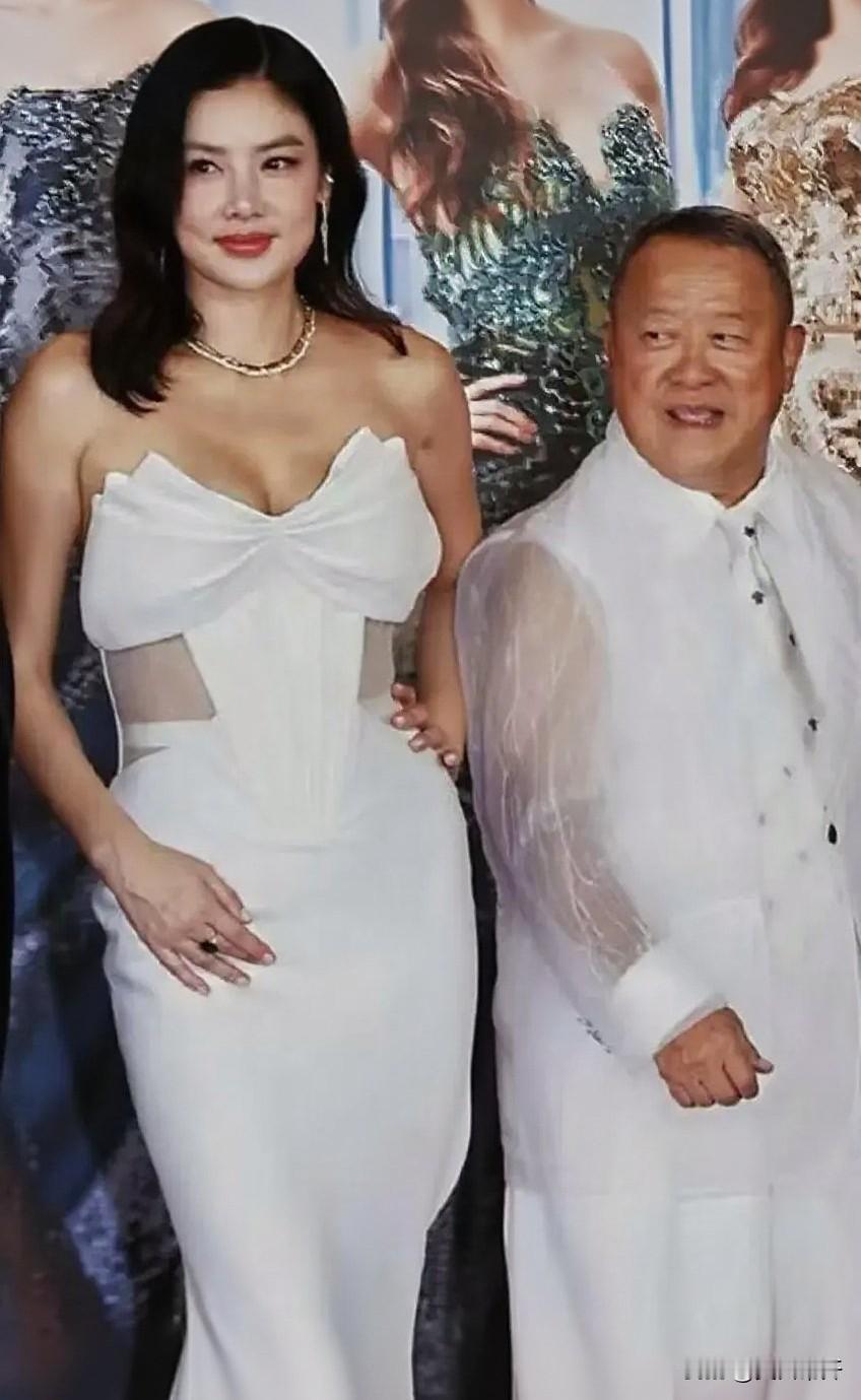 港姐决赛那晚红毯上，曾志伟跟乐基儿并肩合影。她一身白色抹胸长裙，胸前系着大蝴蝶结