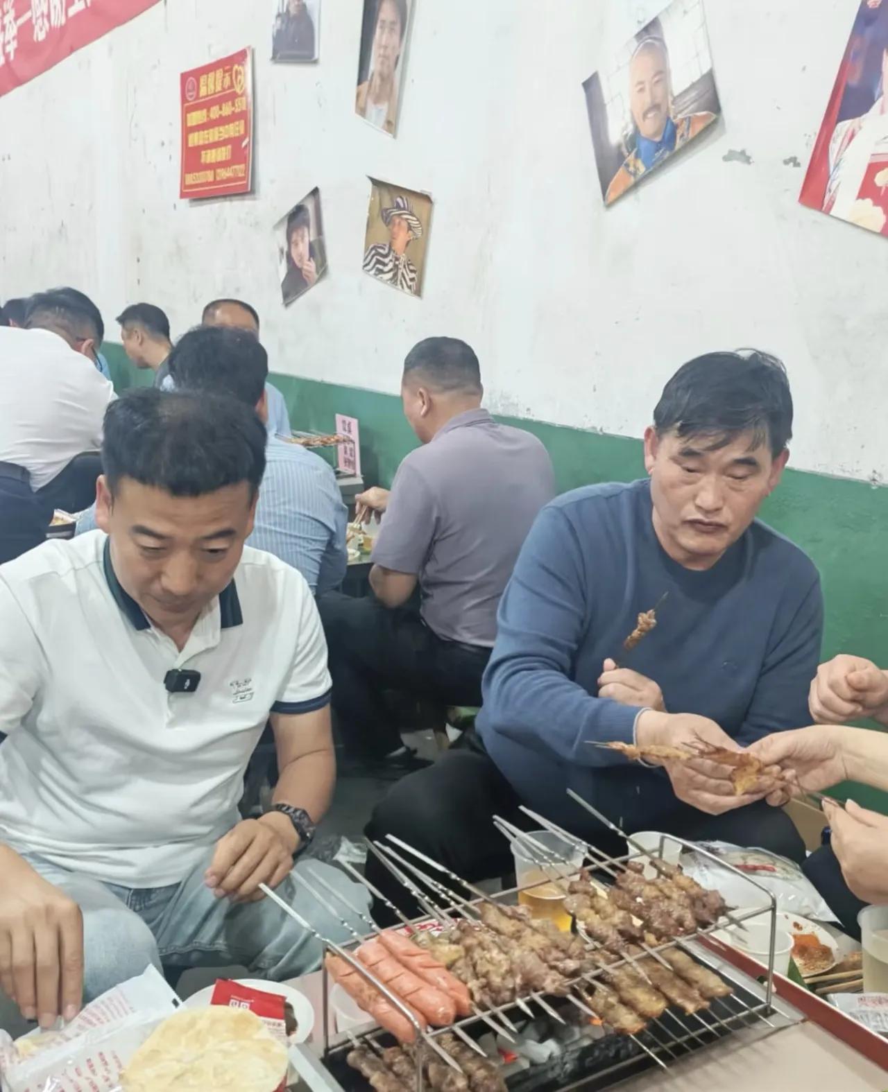大衣哥朱之文现身山东饭店吃烧烤，他坐在小马扎上，和朋友喝啤酒吃烤串，没有半点明星