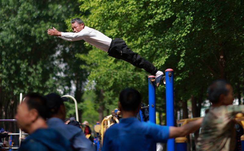 2025年11月1日傍晚，北京丰台花园里，一位六旬老人在单杠上做完14个大回环后