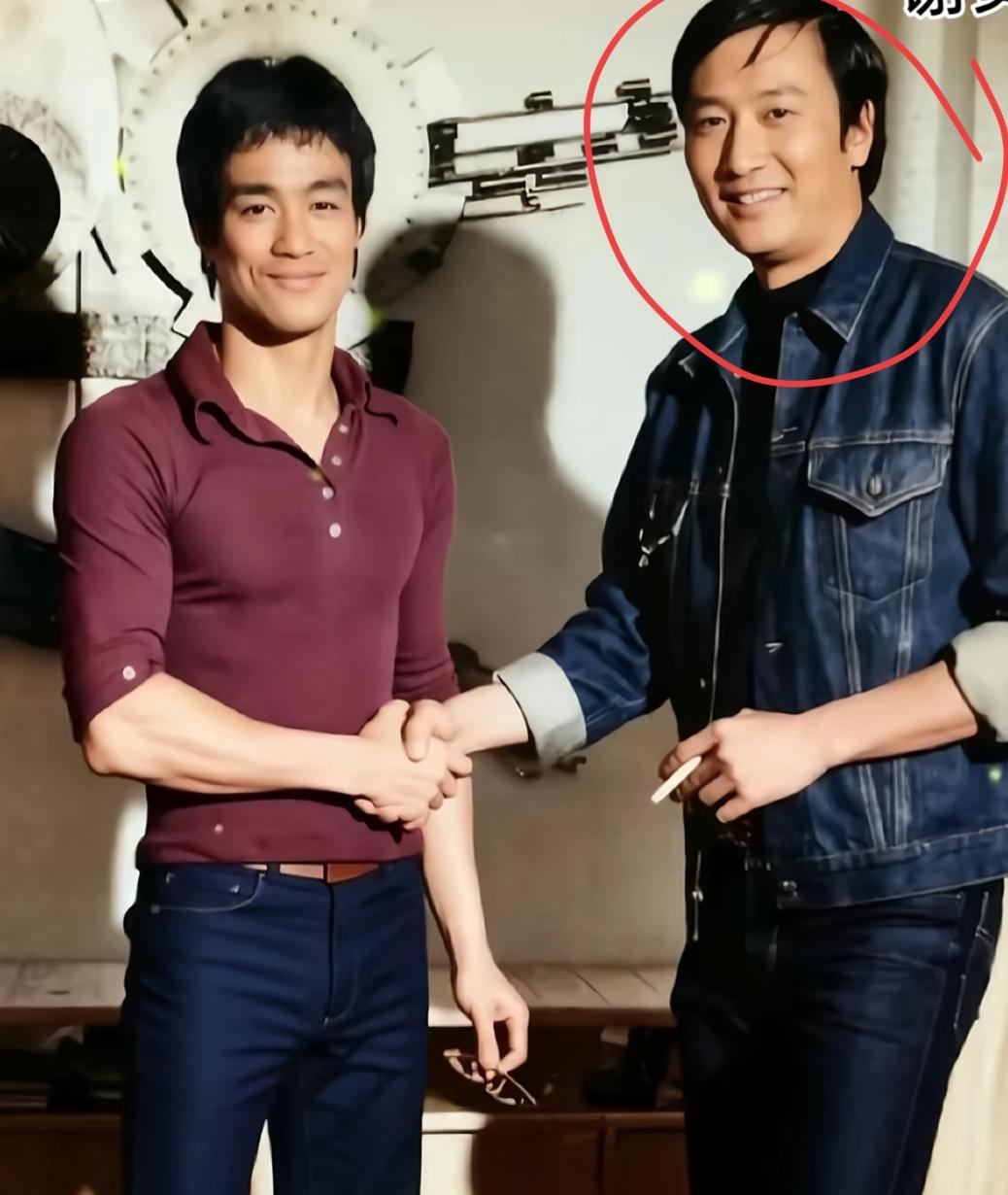 两位男士在握手，背后有个钟表。70年代一张珍贵的合影，李小龙和谁？看看认识他吗？