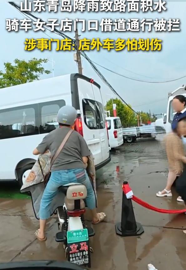 青岛又躺枪了！山东青岛，由于持续降雨，路边积水严重，一位骑电动车的女子试图从一家