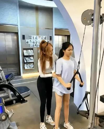 照片里是李湘的女儿王诗龄，在女健身教练的指导下，进行健身锻炼的情景。李湘为了女儿