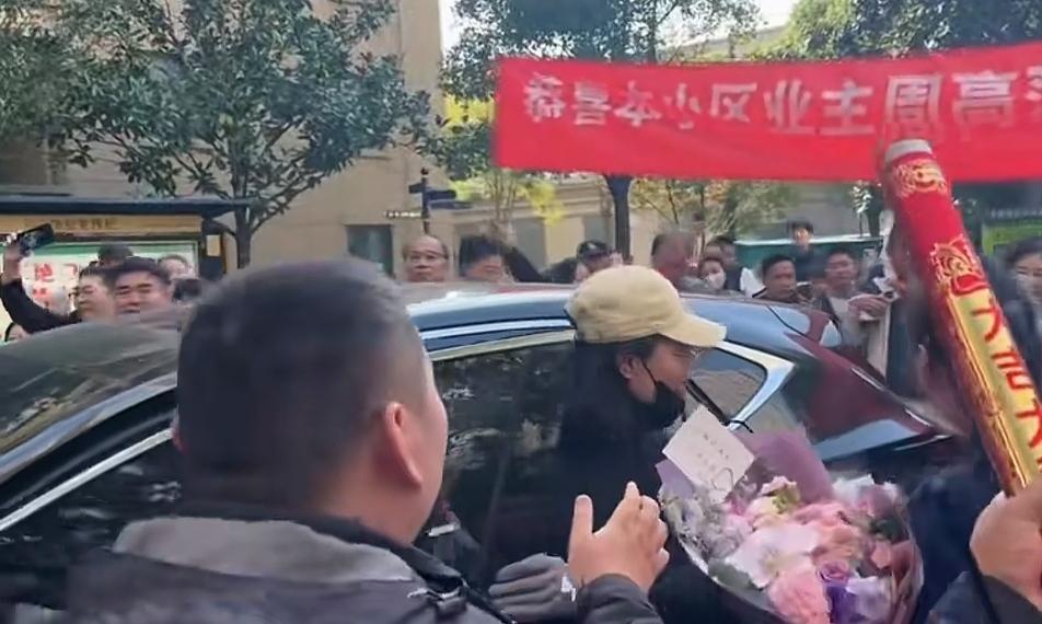 泰州队主教练周高萍女士回到了自己的家中，小区里早已经挤满了人。她下车以后，就