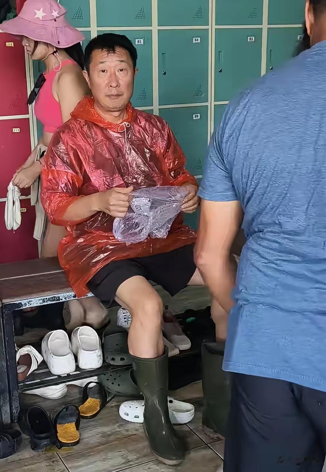 10月5日，57岁林永健现身巴厘岛被偶遇！外穿红色一次性雨衣，独自坐在长凳上换