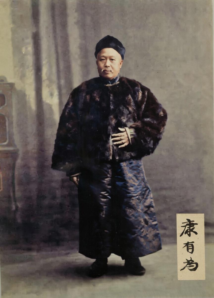 这张照片是康有为在民国时期的标准像，他身着厚重的皮袄与缎面长袍，头戴小帽，神情沉