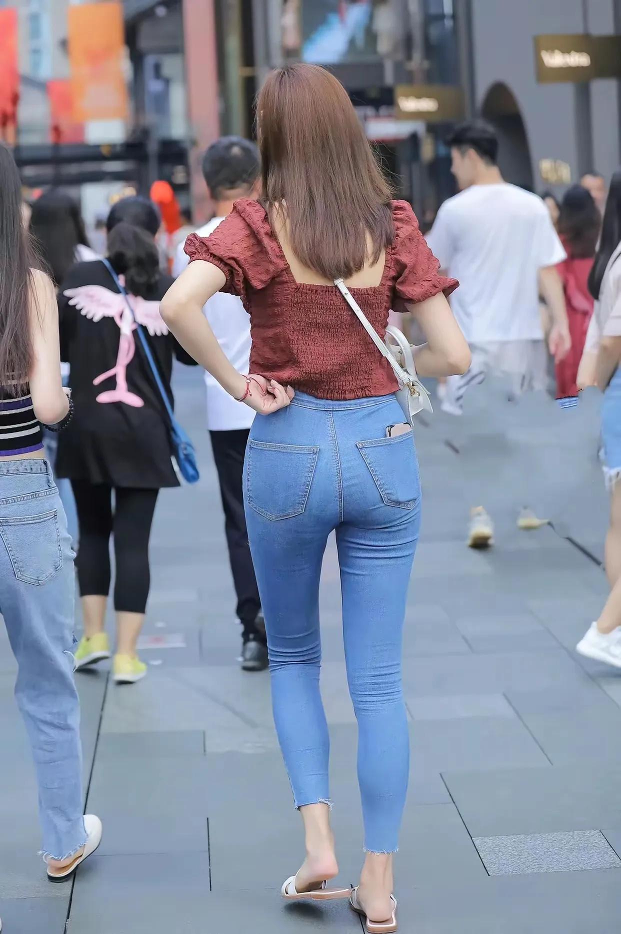 两位并肩站立的女性背影。她们都留着黑色长发，身着黑色短袖上衣。左边的女性穿着蓝色