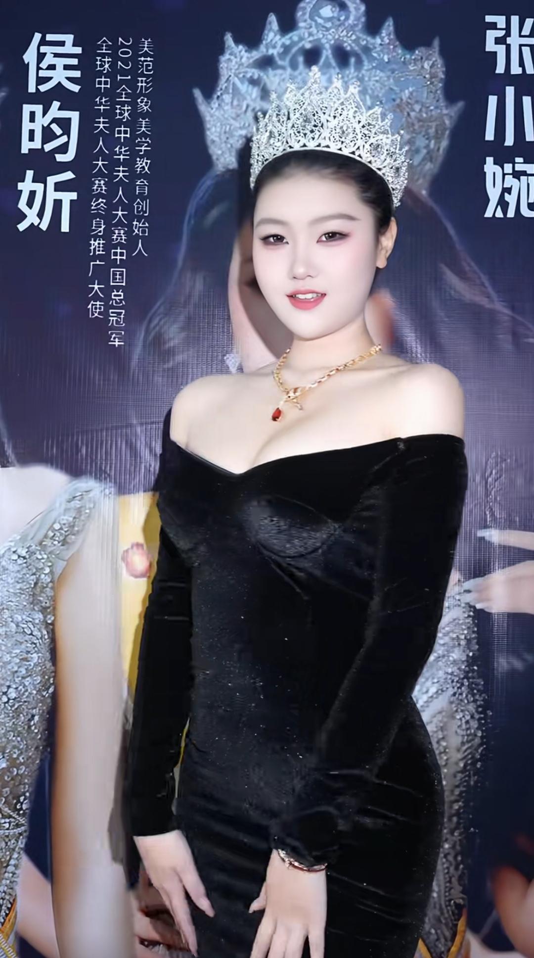这位美女穿着晚礼服，戴着皇冠，看起来非常漂亮。